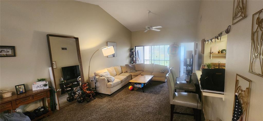 A living room features a beige sectional sofa, a floor lamp, and a large mirror — 2229 PARKLAKE POINT UNIT G7, VENICE, FL