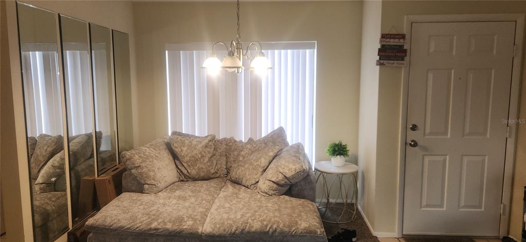 A room features a large gray sectional sofa, a chandelier, mirrored wall panels, and a door — 2229 PARKLAKE POINT UNIT G7, VENICE, FL