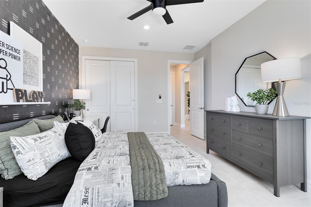 A bedroom features a dark accent wall, a gray dresser, and a bed with patterned bedding — 346 CRYSTAL WOOD DRIVE, WINTER GARDEN, FL
