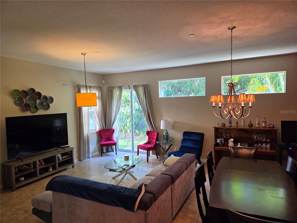 This living and dining area features a large television, a sectional sofa, and a chandelier — 98 S HIGHLAND AVENUE UNIT 2002, TARPON SPRINGS, FL