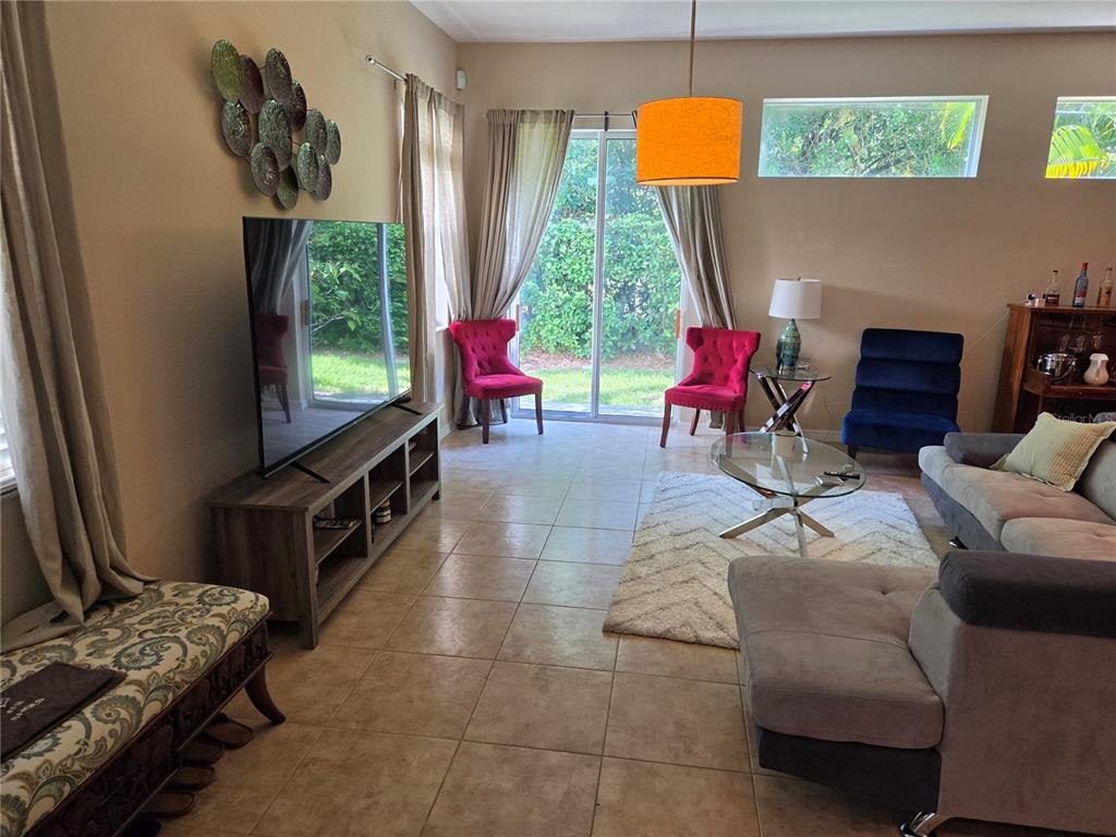A living room features tile flooring, a television on a console, and sliding glass doors — 98 S HIGHLAND AVENUE UNIT 2002, TARPON SPRINGS, FL