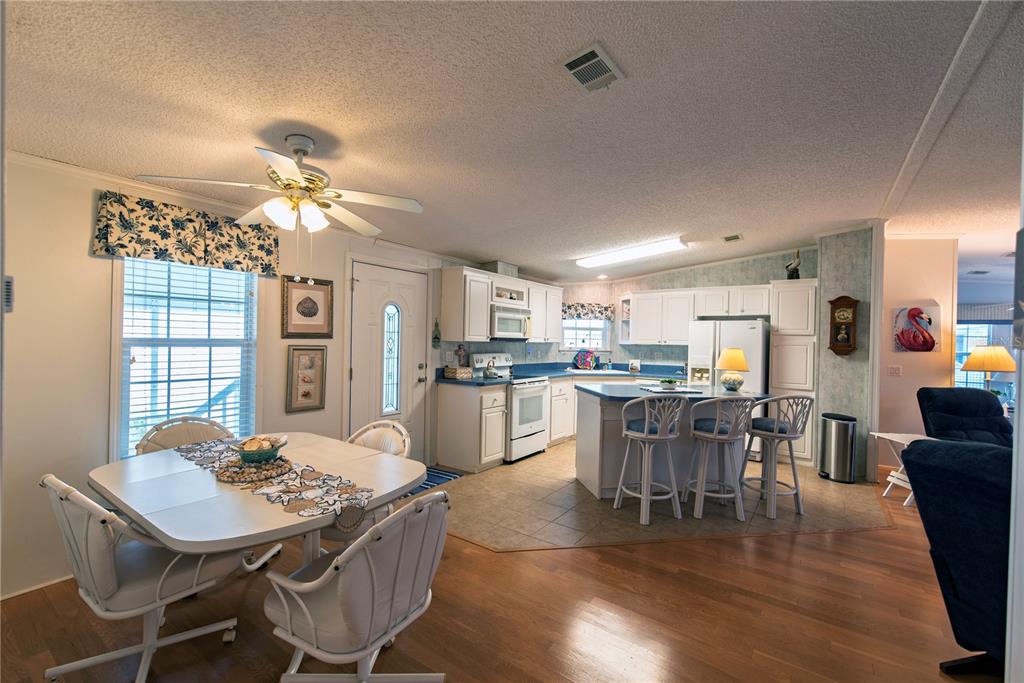 An open-concept kitchen and dining area with white cabinets, blue countertops, and wood flooring — 22 BELCHER DRIVE, PUNTA GORDA, FL