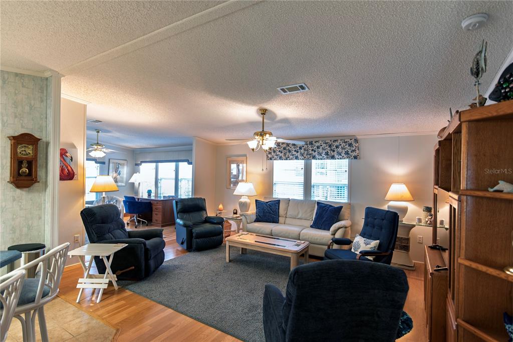 A living room features a beige sofa, blue recliners, a wooden coffee table, and hardwood floors — 22 BELCHER DRIVE, PUNTA GORDA, FL