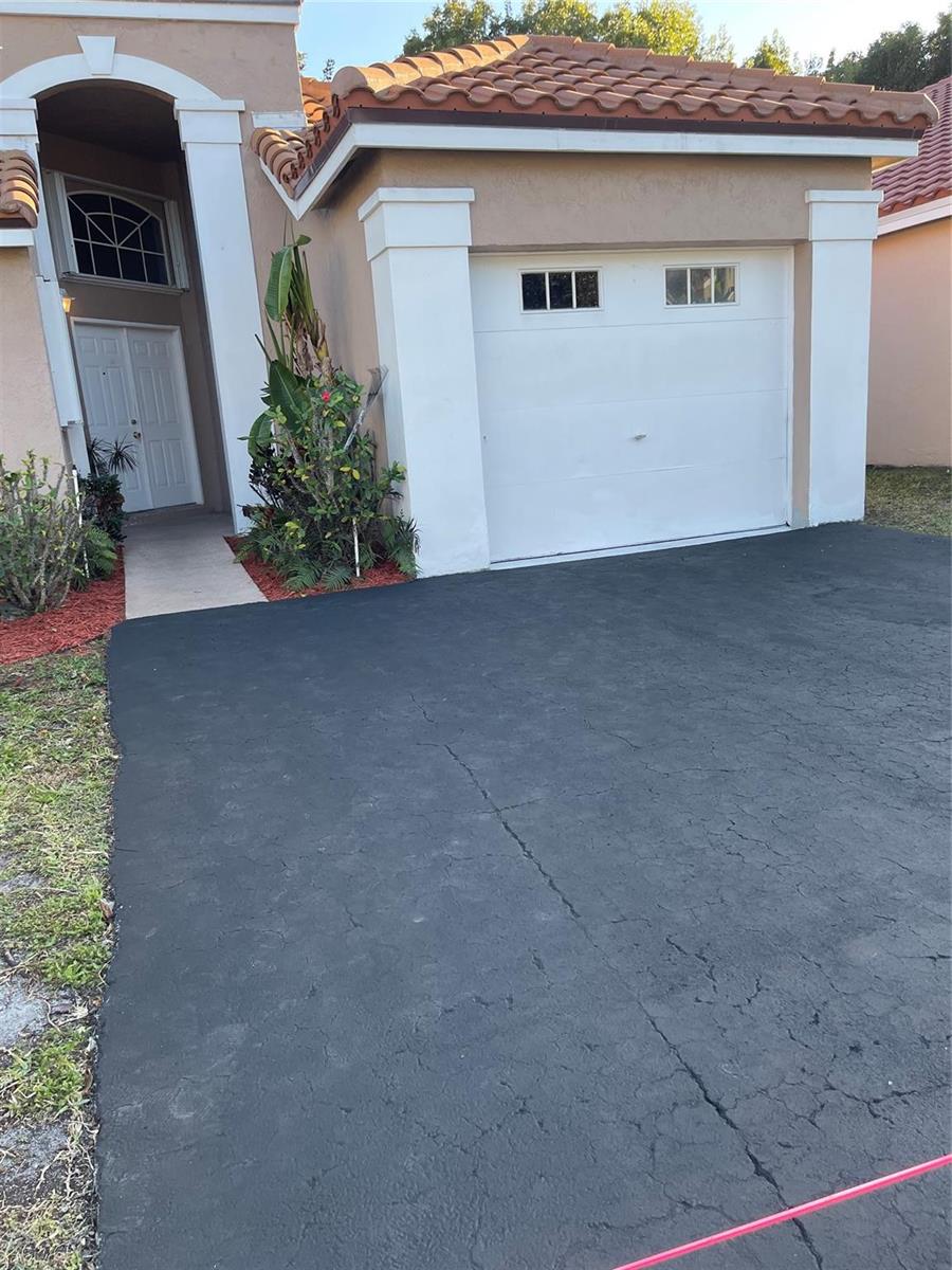 A single-story house exterior features a white garage door, a paved driveway, and a front entrance — 480 Somerset Way, Weston FL 33326, WESTON, FL