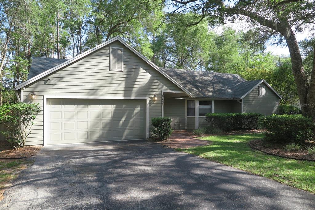 A single-story house with light green siding, a two-car garage, and a paved driveway — 8215 SW 47TH ROAD, GAINESVILLE, FL