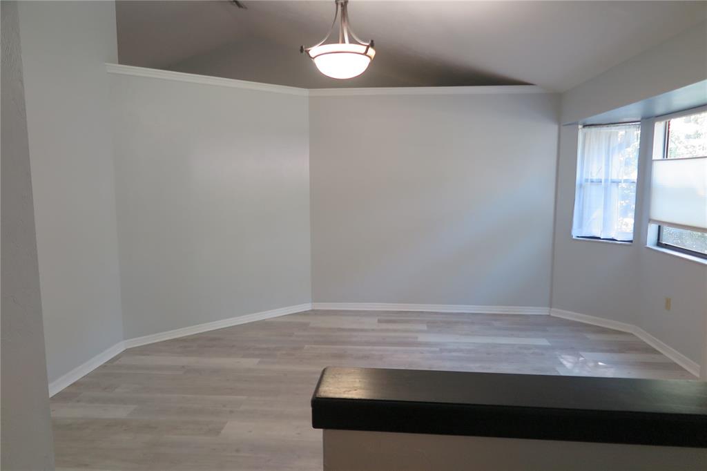 An empty room with light wood-look flooring, a vaulted ceiling, and a hanging light fixture — 8215 SW 47TH ROAD, GAINESVILLE, FL