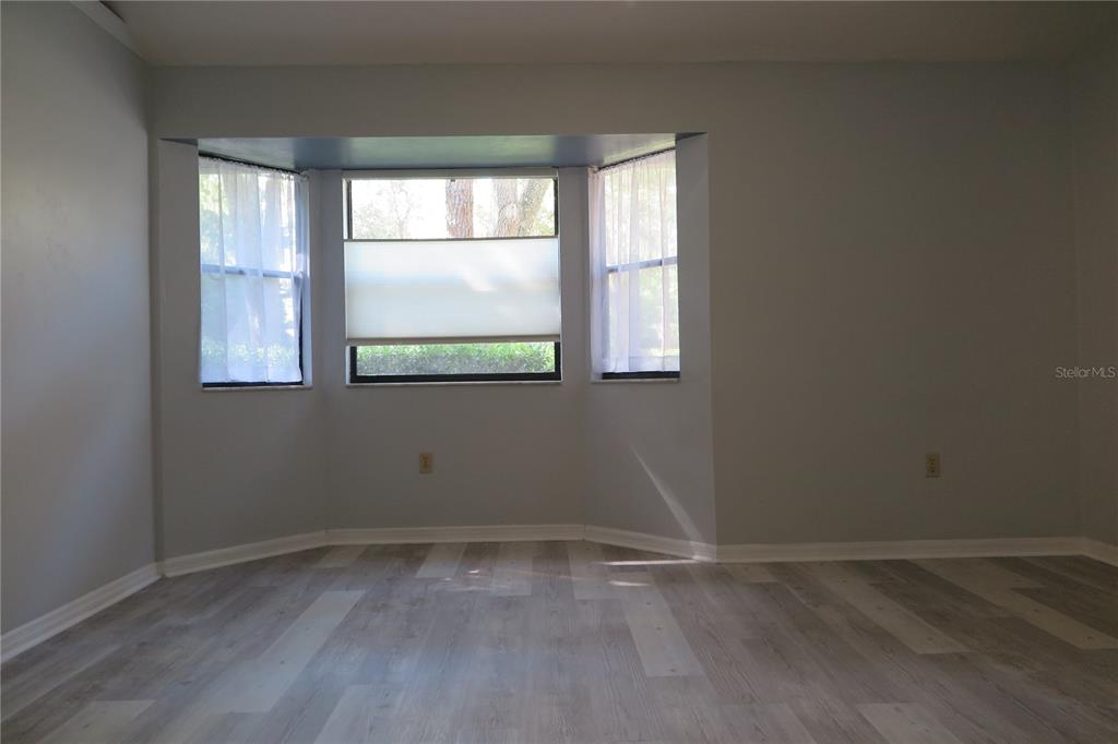 A room with light gray walls, wood-look flooring, and a central bay window — 8215 SW 47TH ROAD, GAINESVILLE, FL
