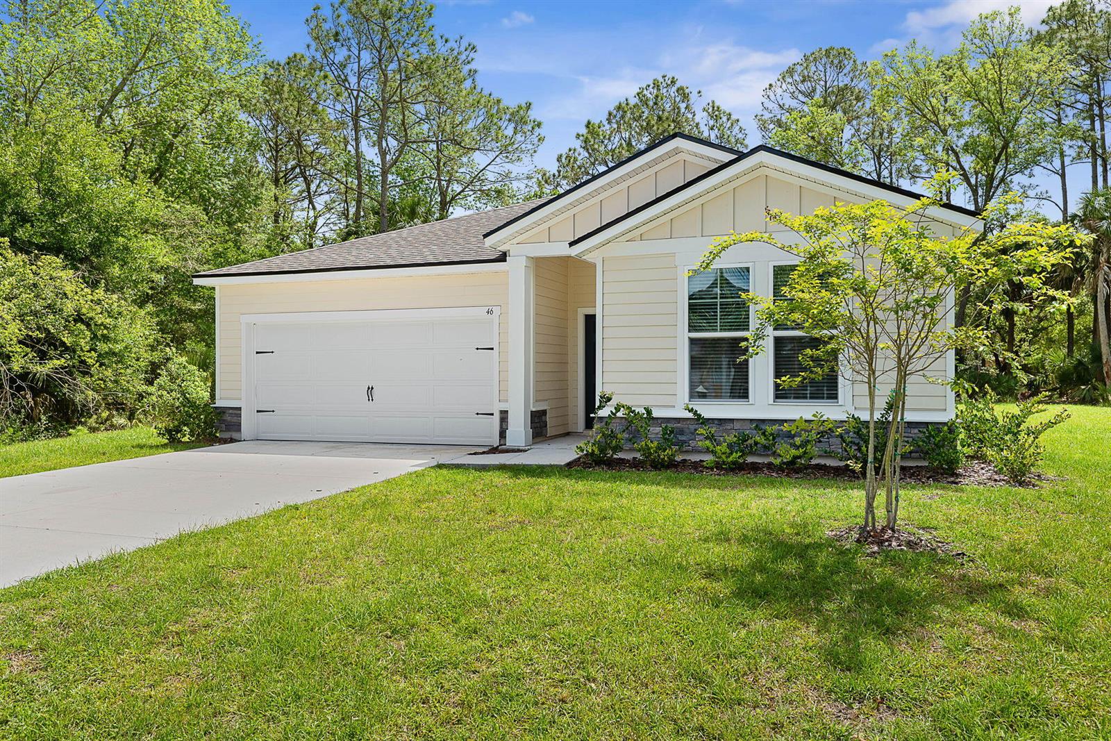 A single-story house with beige siding, a two-car garage, and a stone-accented front facade — 46 Poplar Drive, Palm Coast FL 32164, PALM COAST, FL