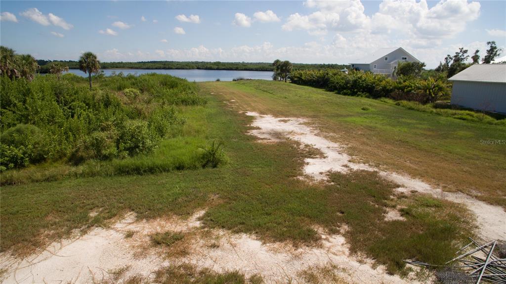 An elevated view of a grassy, sandy lot leading toward a body of water — DEER COURT, VENICE, FL