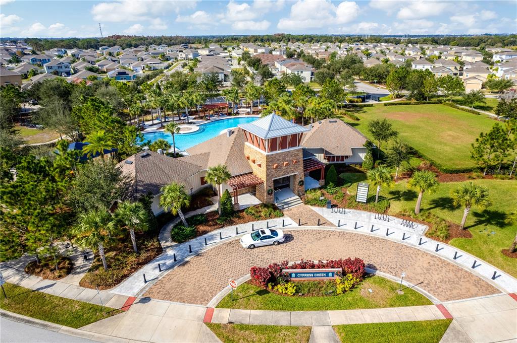 An aerial view shows a community clubhouse with a pool, parking area, and landscaping — 15501 WICKED STRONG STREET, SUN CITY CENTER, FL