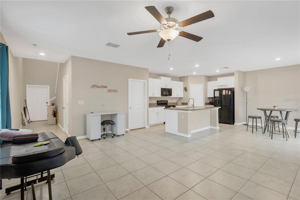 An open-concept kitchen and living area features tile flooring, white cabinetry, and a ceiling fan — 15501 WICKED STRONG STREET, SUN CITY CENTER, FL