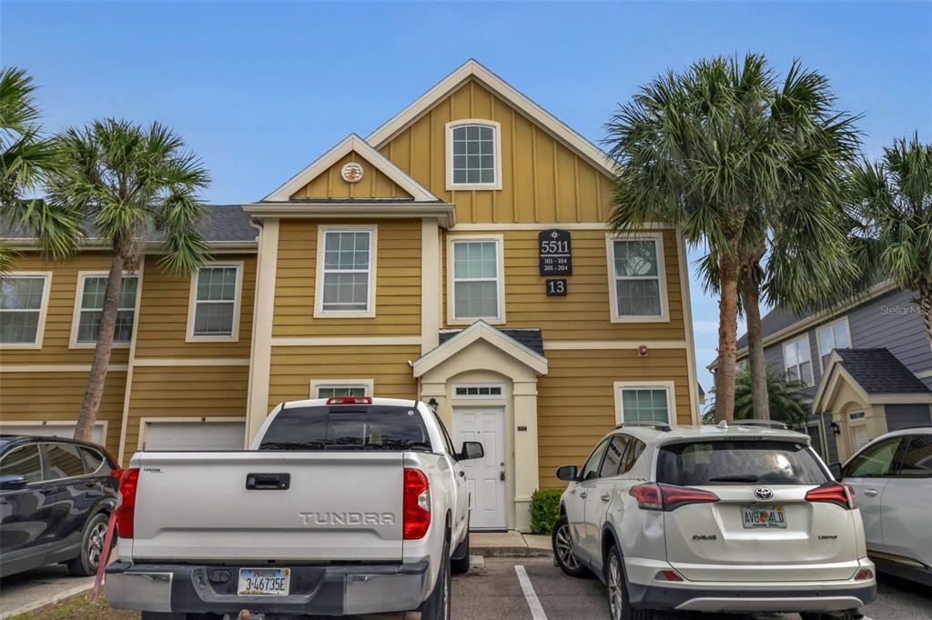 A two-story yellow building with a white front door and two parked cars — 5511 ROSEHILL ROAD UNIT 203, SARASOTA, FL