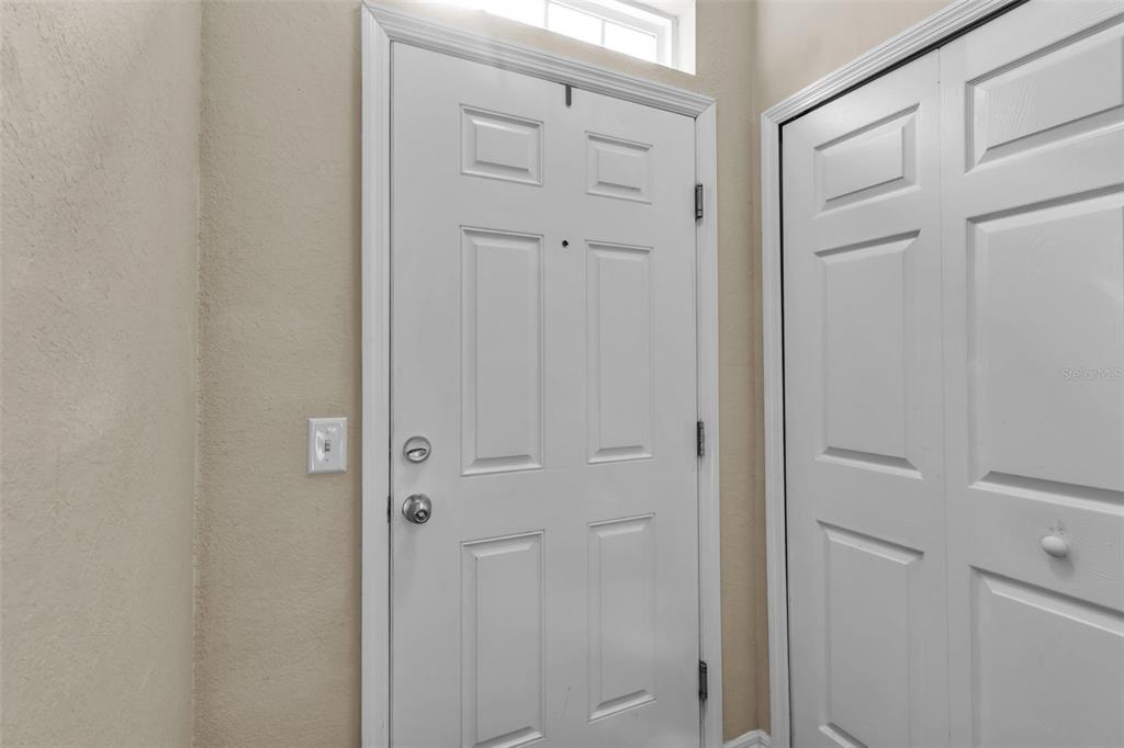A white front door with a transom window sits next to a white closet door — 5511 ROSEHILL ROAD UNIT 203, SARASOTA, FL