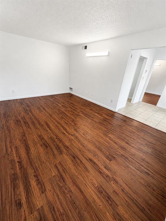 An empty room with wood-look flooring, white walls, and a doorway leading to a tiled area — 1745-1745 NE 2ND STREET UNIT 2, OCALA, FL