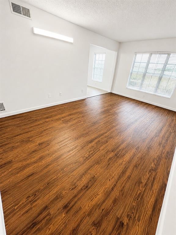 An empty room with wood-look flooring, white walls, and a window with blinds — 1745-1745 NE 2ND STREET UNIT 2, OCALA, FL