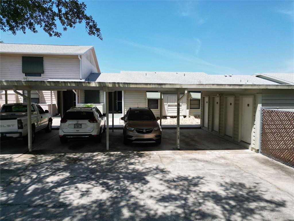 A covered carport area features three parked vehicles and several storage unit doors — 4317 TIBURON DRIVE, NEW PORT RICHEY, FL