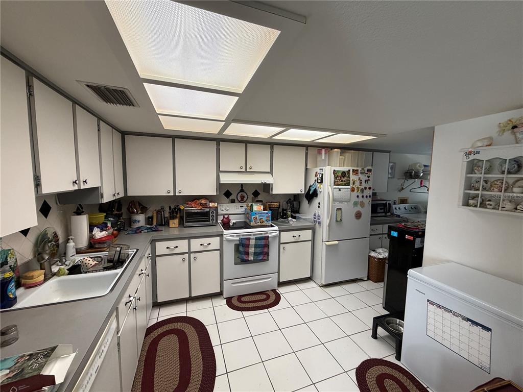 A kitchen with white cabinets, tile flooring, a white stove, and a refrigerator — 4317 TIBURON DRIVE, NEW PORT RICHEY, FL
