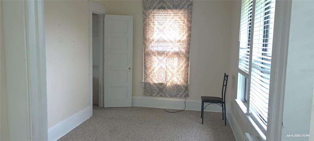 A bedroom with beige walls, carpeted flooring, a single chair, and a window with blinds — 108 MURRAY WAY UNIT 1, SOUTH DAYTONA, FL