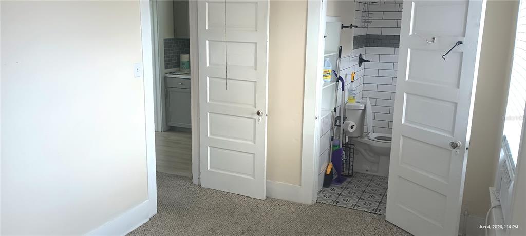A room with carpeted flooring features two white doors, one leading to a tiled bathroom — 108 MURRAY WAY UNIT 1, SOUTH DAYTONA, FL