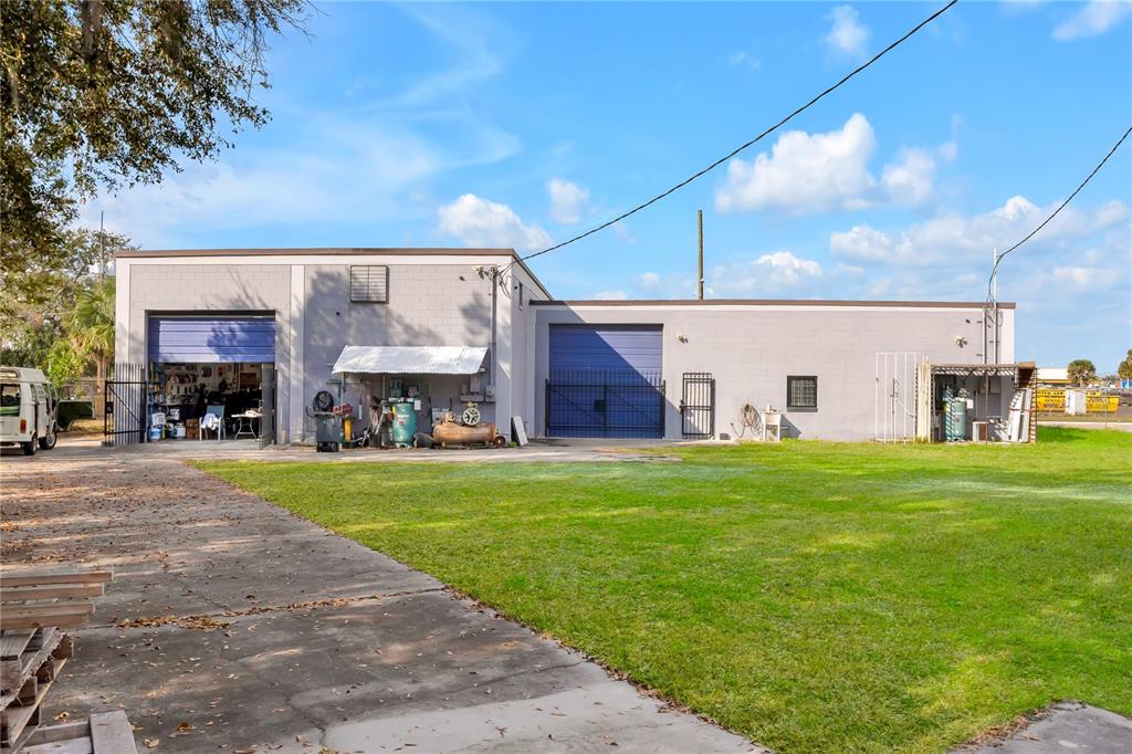An exterior view of a gray industrial building with two blue roll-up garage doors — 41 N DOLLINS AVENUE, ORLANDO, FL