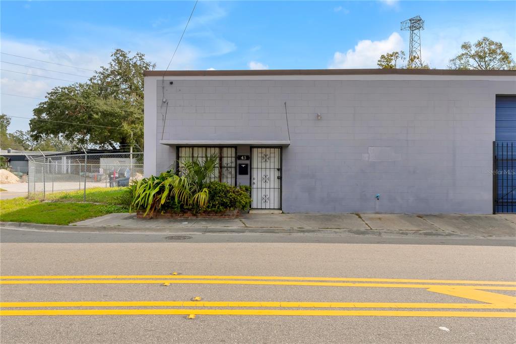 A gray concrete block commercial building features a single entrance door and a front window — 41 N DOLLINS AVENUE, ORLANDO, FL