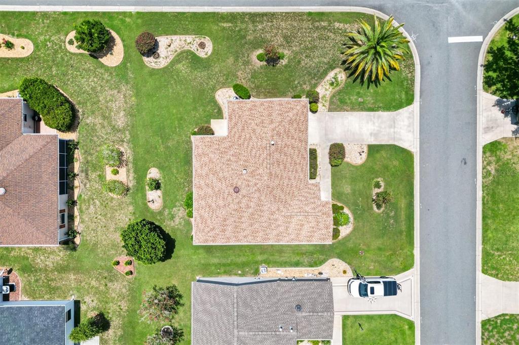 An aerial view shows a house with a tan roof surrounded by a landscaped lawn — 1630 ABERCROMBIE WAY, THE VILLAGES, FL