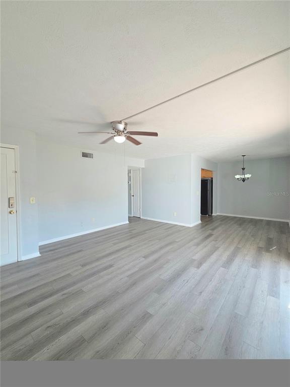 An open-concept living and dining area features light gray wood-look flooring and a ceiling fan — 13690 ORANGE SUNSET DRIVE UNIT 102, TAMPA, FL