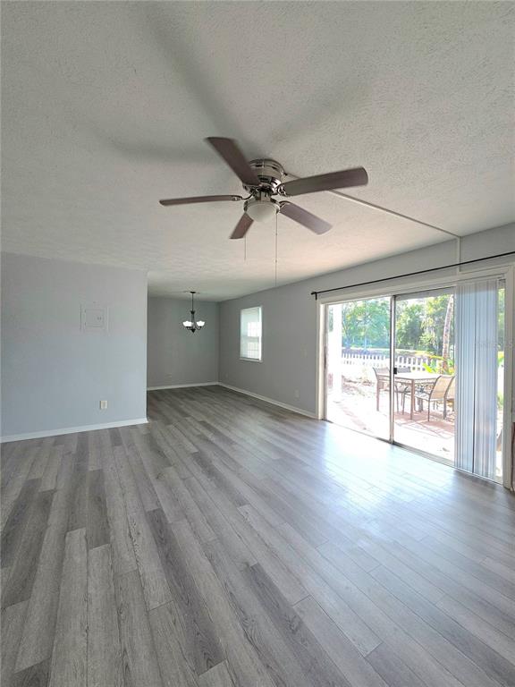 A living room with gray wood-look flooring, a ceiling fan, and sliding glass patio doors — 13690 ORANGE SUNSET DRIVE UNIT 102, TAMPA, FL