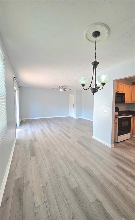 An open-concept living and dining area features light wood-look flooring and a hanging chandelier — 13690 ORANGE SUNSET DRIVE UNIT 102, TAMPA, FL