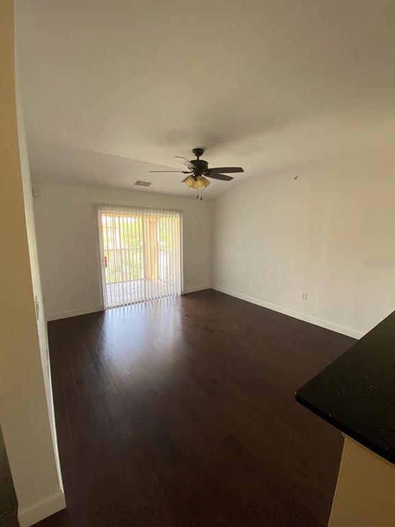 A kitchen with dark countertops and white cabinets opens into a living area with flooring — 5475 VINELAND ROAD UNIT 8311, ORLANDO, FL