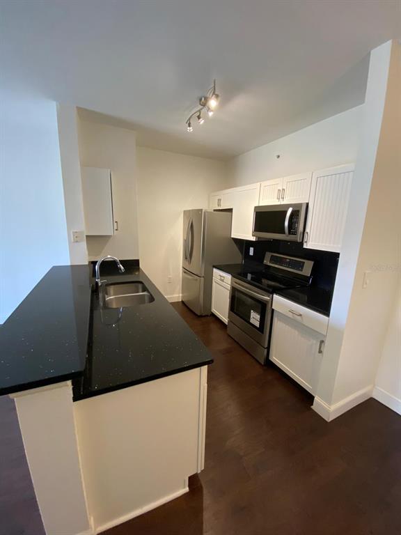 A dining area features dark hardwood flooring, a single pendant light, and white walls — 5475 VINELAND ROAD UNIT 8311, ORLANDO, FL