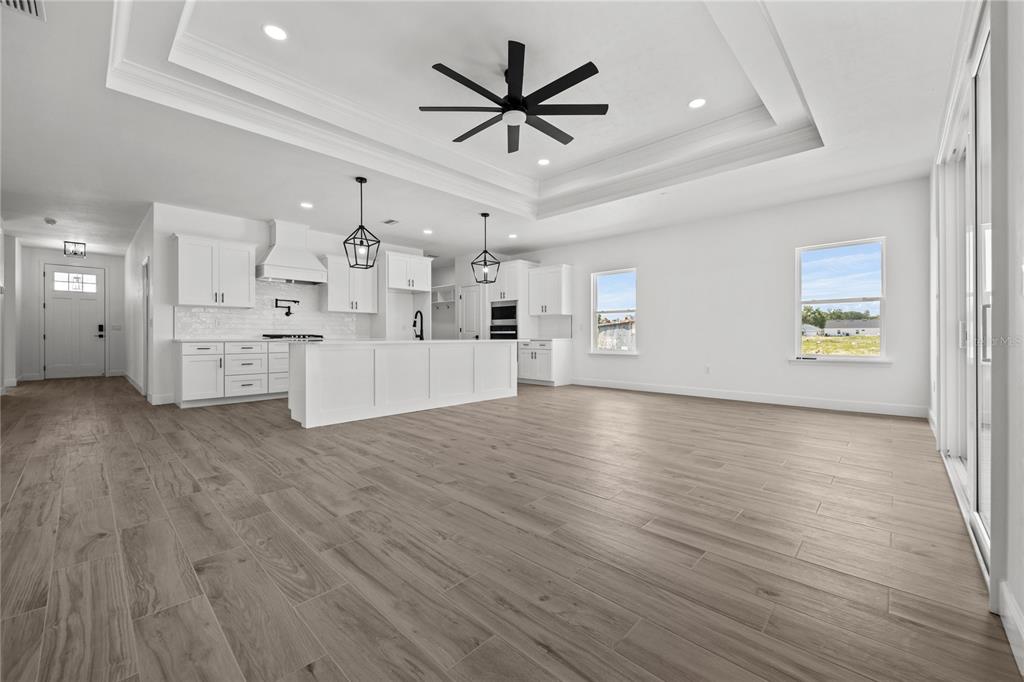 A bright, open-concept kitchen and living area featuring white cabinetry, a large island, and wood-look flooring — 1050 SW 67TH WAY, GAINESVILLE, FL