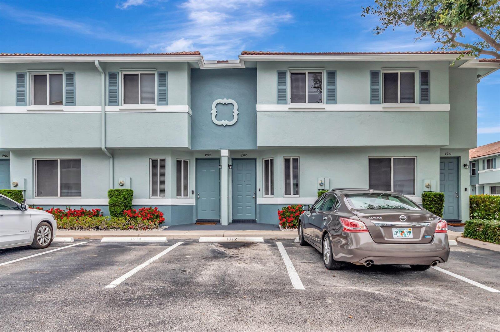 A two-story apartment building exterior features light blue siding, two front doors, and parking spaces — 1912 Hibiscus Lane, Riviera Beach FL 33404, RIVIERA BEACH, FL