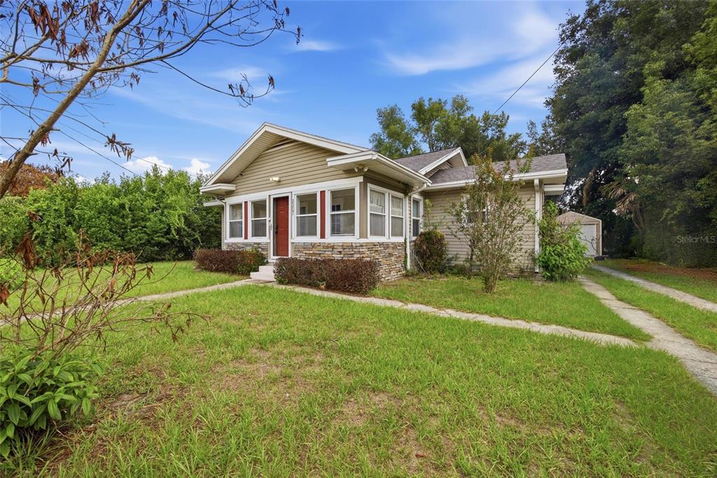 A single-story house with tan siding, a stone facade, and a red front door — 2207 AVENUE F NW, WINTER HAVEN, FL