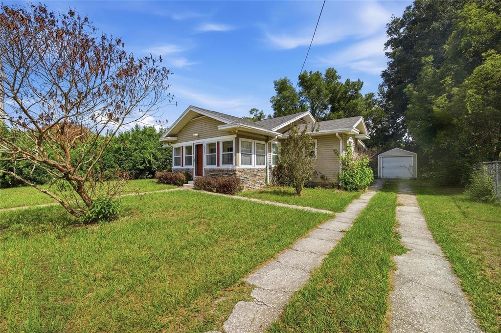 A single-story house with tan siding, a stone base, and a detached garage — 2207 AVENUE F NW, WINTER HAVEN, FL