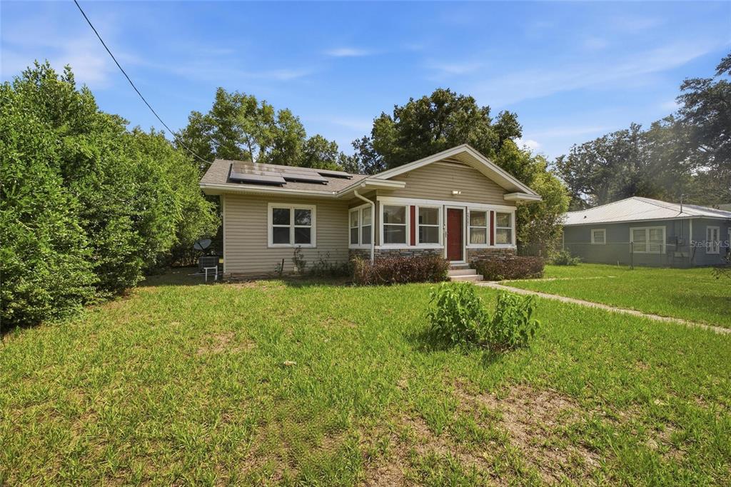 A single-story house with tan siding, a front porch, and solar panels on the roof — 2207 AVENUE F NW, WINTER HAVEN, FL