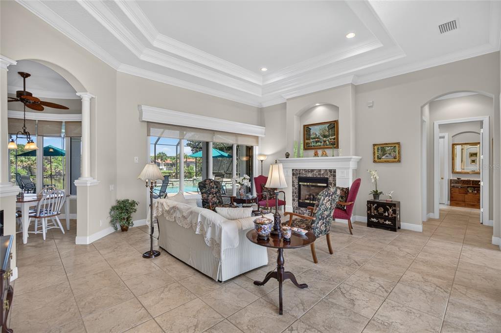 A living room with a fireplace, tile floors, tray ceiling, and sliding doors to a pool — 32 SAN GABRIEL LANE, PALM COAST, FL
