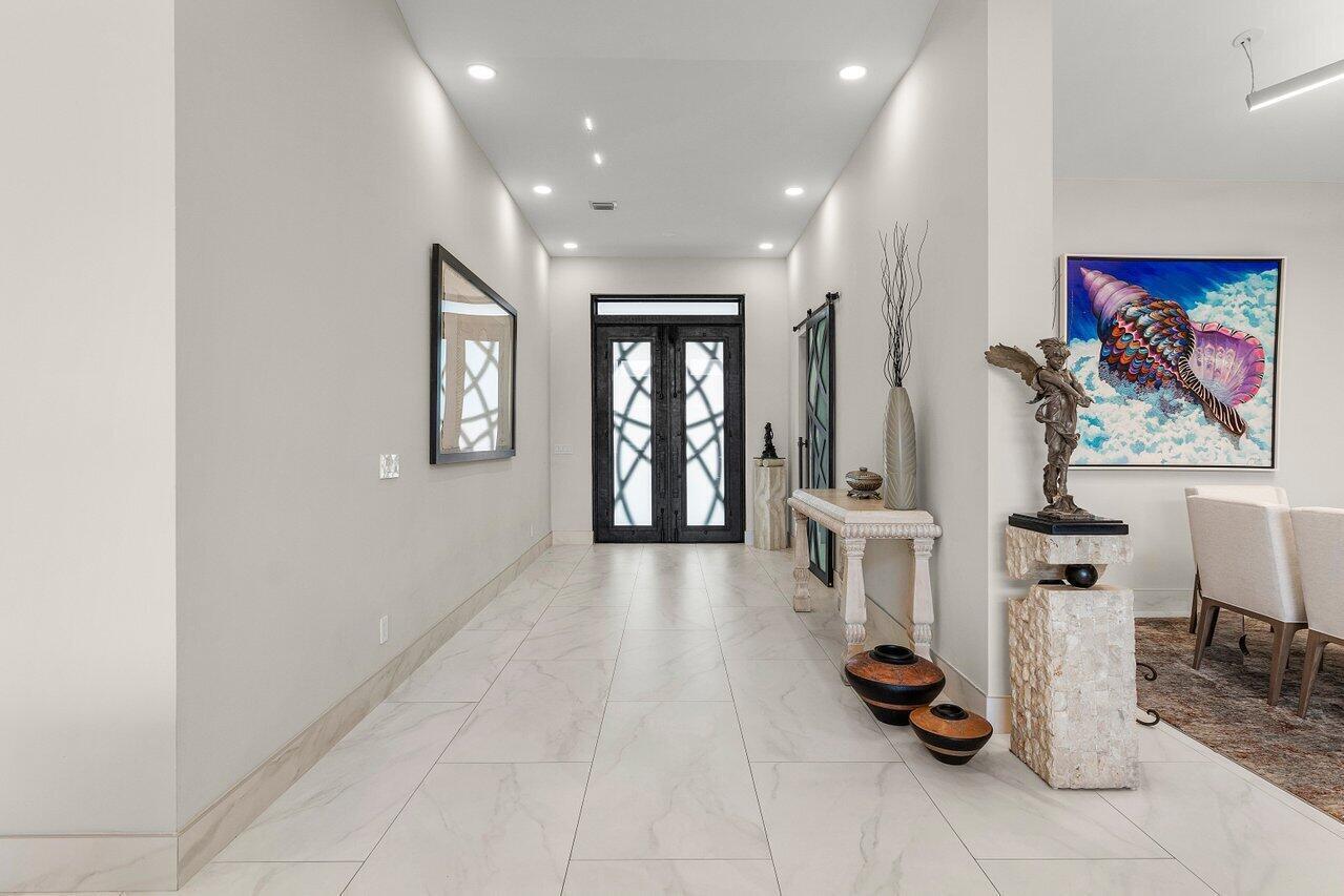 A bright entryway features white tile floors, a dark double door, and decorative art pieces — 11164 Boca Woods Lane, Boca Raton FL 33428, BOCA RATON, FL