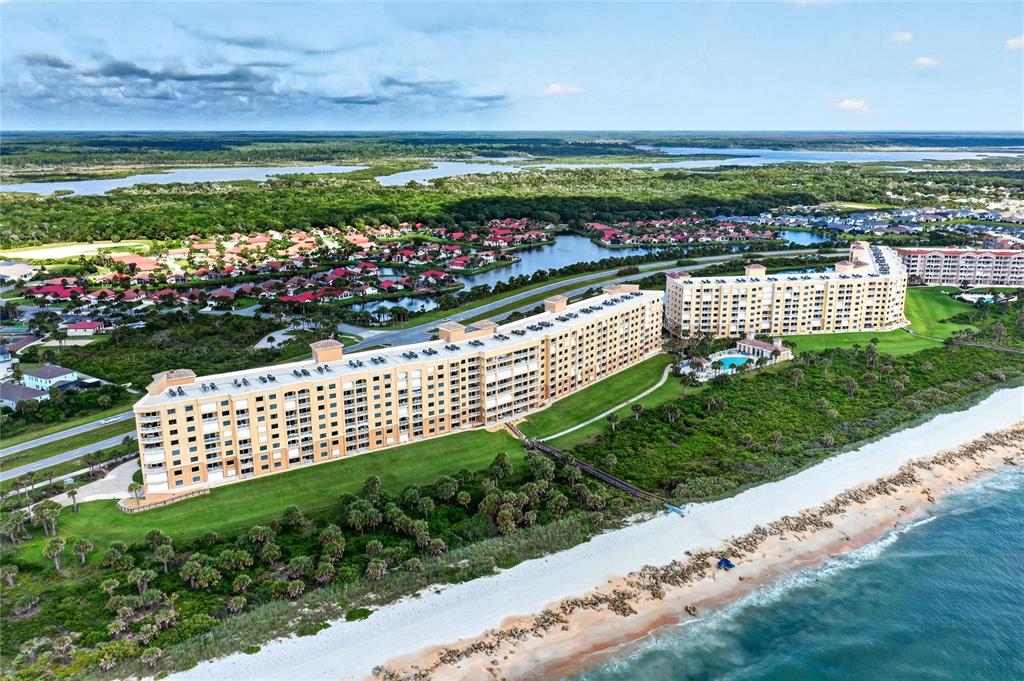 An aerial view shows two large beachfront condominium buildings surrounded by green space and water — 60 SURFVIEW DRIVE UNIT 206, PALM COAST, FL