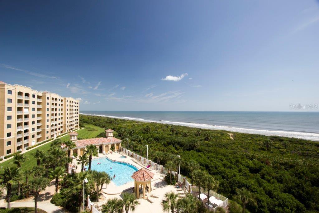 An aerial view shows a beachfront resort with a swimming pool, palm trees, and ocean — 60 SURFVIEW DRIVE UNIT 206, PALM COAST, FL