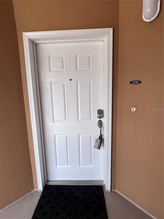 A white front door with a keypad lock and a black mat at the entrance — 60 SURFVIEW DRIVE UNIT 206, PALM COAST, FL