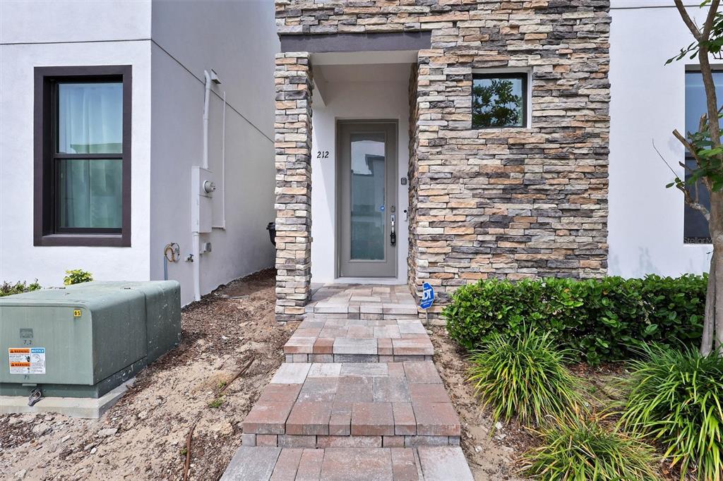The exterior of a modern home features a stone-clad entrance and a paved walkway — 212 VILLA DOMANI CIRCLE, DAVENPORT, FL