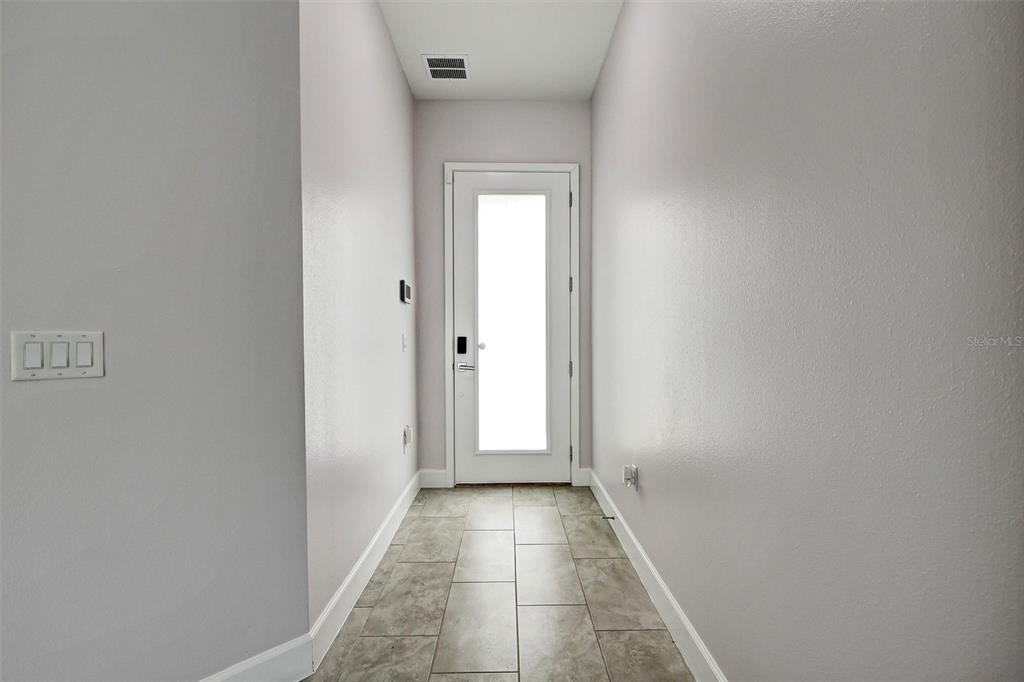 A narrow entryway features light gray walls, tile flooring, and a white door with glass — 212 VILLA DOMANI CIRCLE, DAVENPORT, FL