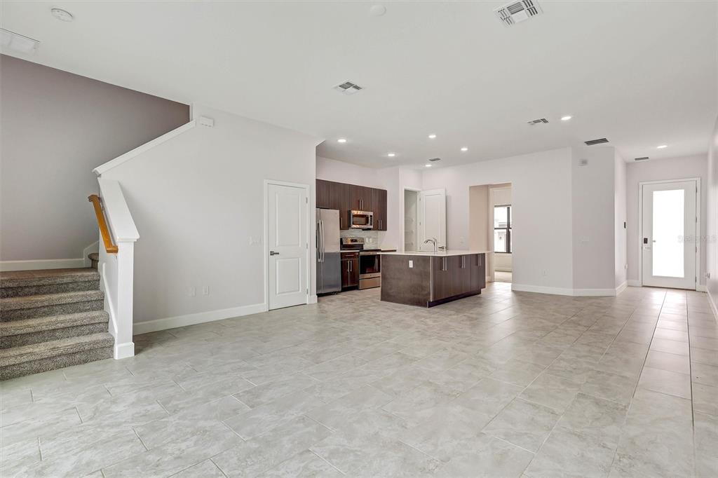 An open-concept kitchen and living area features tile flooring, a center island, and carpeted stairs — 212 VILLA DOMANI CIRCLE, DAVENPORT, FL