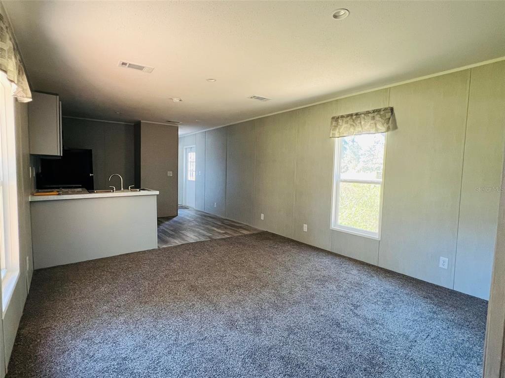A bedroom features a wooden bed frame, green bedding, a dresser, and a woven rug — 11651 SE 82ND STREET, MORRISTON, FL