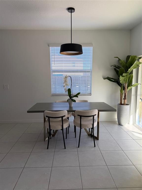 A kitchen with white cabinets and stainless steel appliances overlooks a dining area with tile floors — 10268 HONEY HAMMOCK WAY UNIT 10268, SAN ANTONIO, FL
