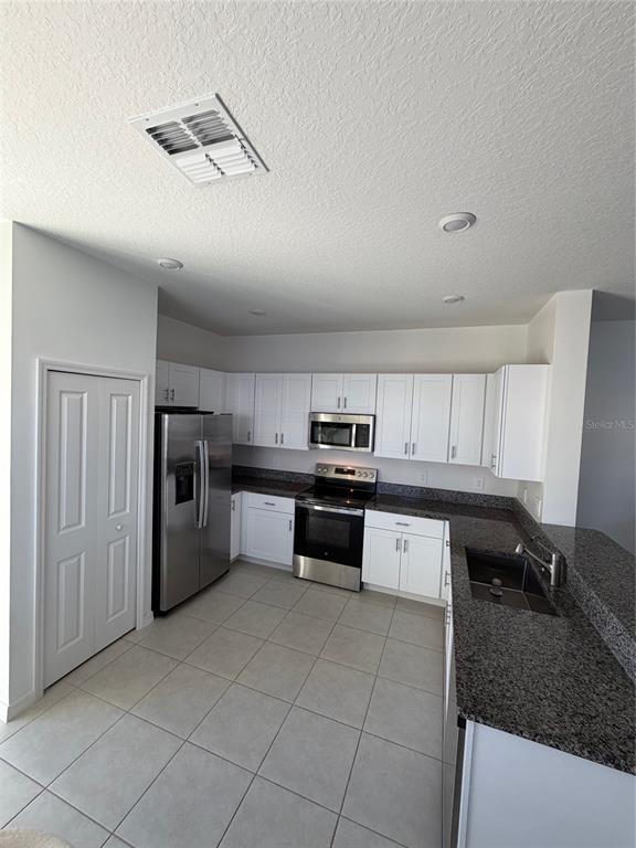 A kitchen with white cabinets, stainless steel appliances, and dark granite countertops — 10268 HONEY HAMMOCK WAY UNIT 10268, SAN ANTONIO, FL