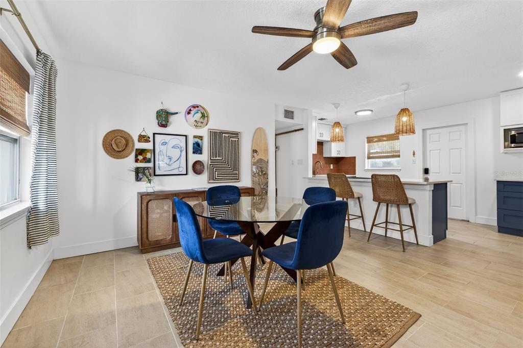 A dining area features a glass table, blue velvet chairs, and a rattan sideboard — 101 40TH AVENUE SE, ST PETERSBURG, FL