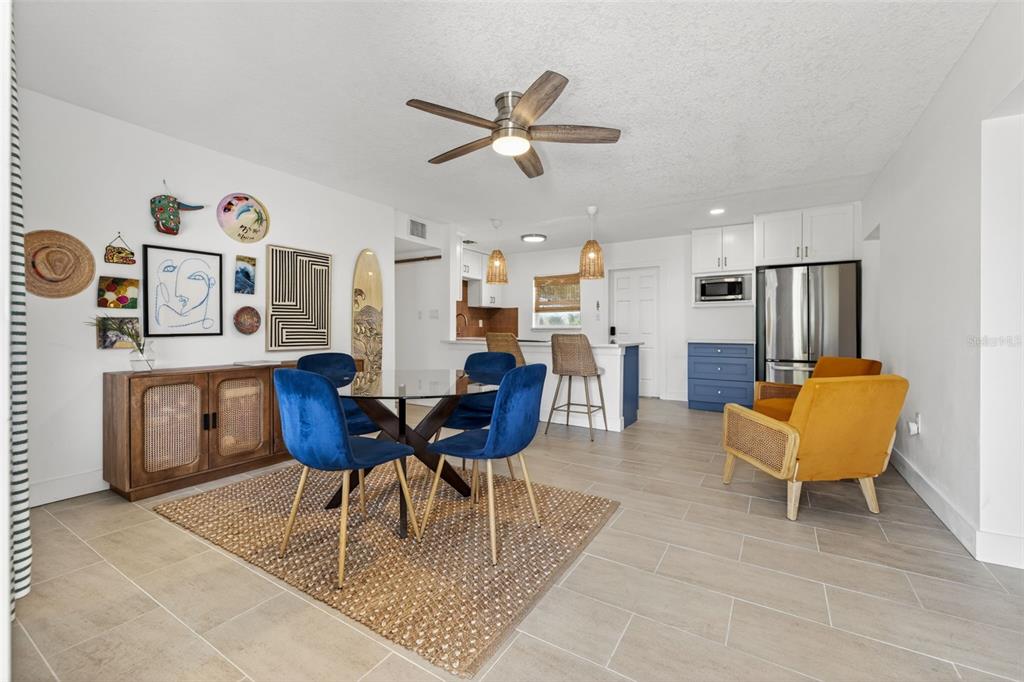 A dining area with blue velvet chairs, a glass table, and a nearby kitchen — 101 40TH AVENUE SE, ST PETERSBURG, FL