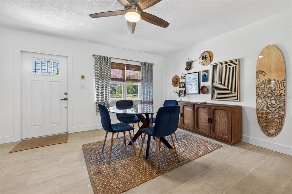 A dining room features a glass table, blue chairs, a wooden sideboard, and a surfboard — 101 40TH AVENUE SE, ST PETERSBURG, FL